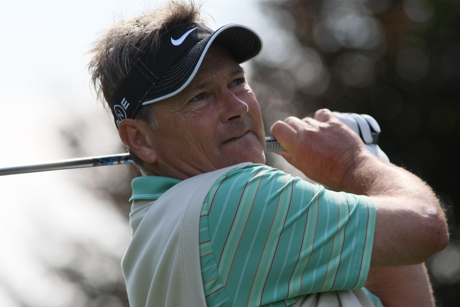 A golfer held in the finish position, weight on the lead foot, trail heel raised and chest turned toward the target.