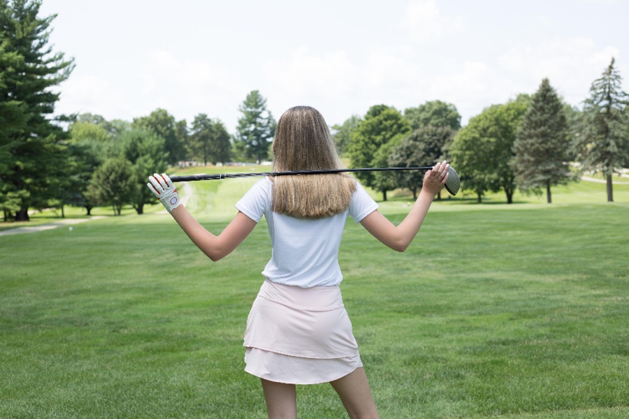 A golfer photographed from behind at the top of the backswing, shoulders turned well past the hips, club above the trail shoulder.